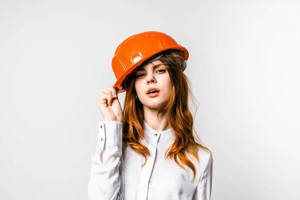 Confiante bela menina ruiva em camisa branca e laranja capacete protetor posando, olhando para a câmera — Fotografia de Stock