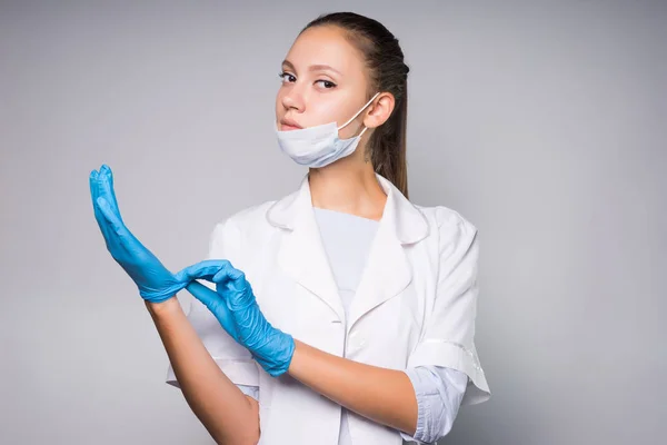 흰색 의료 드레싱 가운에 지능형 심각한 여자 의사 손에 블루 실리콘 장갑에 박 았 — 스톡 사진