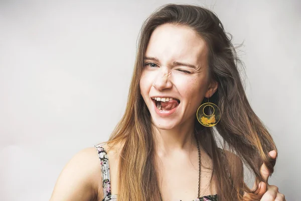 Mujer cara divertida muestra la lengua, en pendientes de moda, se ve feliz — Foto de Stock