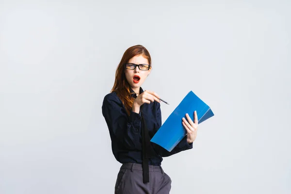 Unzufriedenes böses rothaariges Mädchen mit Brille und blauem Hemd hält Dokumente in ihren Händen und zeigt auf sie — Stockfoto