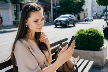 selfie yapıyor sokakta, ahşap bir bankta oturan uzun saçlı çekici kız