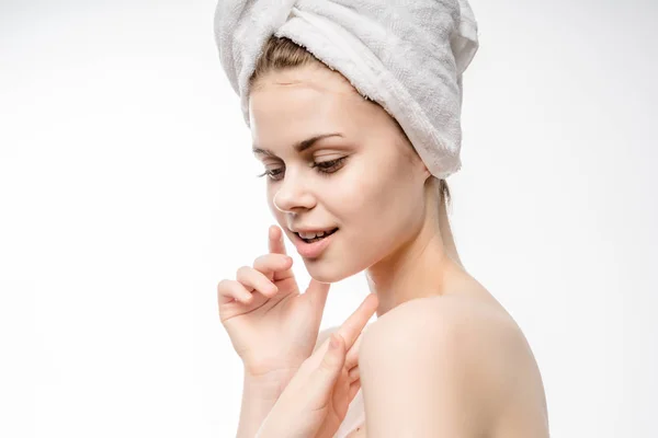 Ein Mädchen mit einem Handtuch auf dem Kopf kümmert sich nach der Dusche um sich selbst — Stockfoto