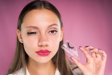 bir genç kız Beyaz gömlekli bir paket tutuyor sahte kirpik, onları bir gözünüz yapıştırılan