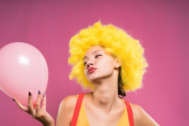 genç kız sarı palyaço peruk başında içinde bir pembe balon elinde tutan, gözleri kapalı