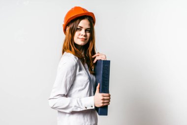 genç kız bir turuncu koruyucu bir klasör belgeler ile tutarak başında miğfer bir beyaz gömlek gülümseyen