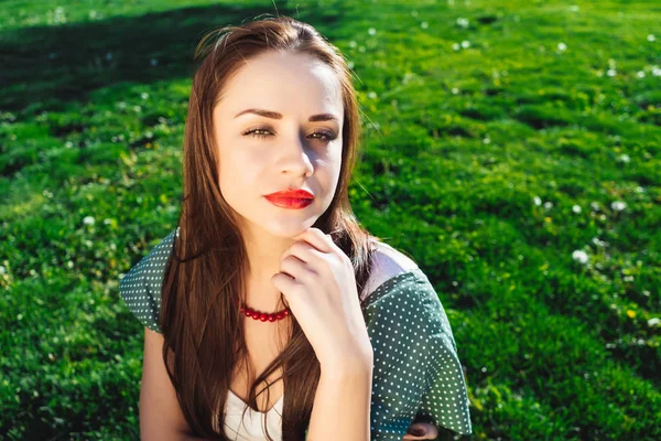 Mujer escéptica posando, sentada sobre hierba verde en el parque, disfrutando del clima — Foto de Stock