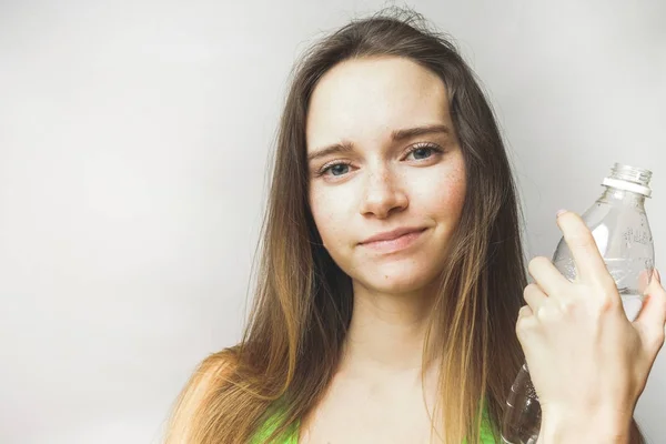 Verbaasd fitness vrouw met fles water, kijkt naar de camera en glimlach — Stockfoto