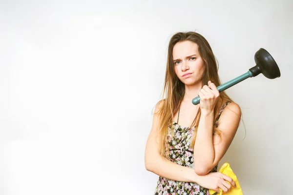 The dissatisfied young girl holds in her hands the plunger and yellow rubber gloves, does not want to do cleaning — Stock Photo, Image