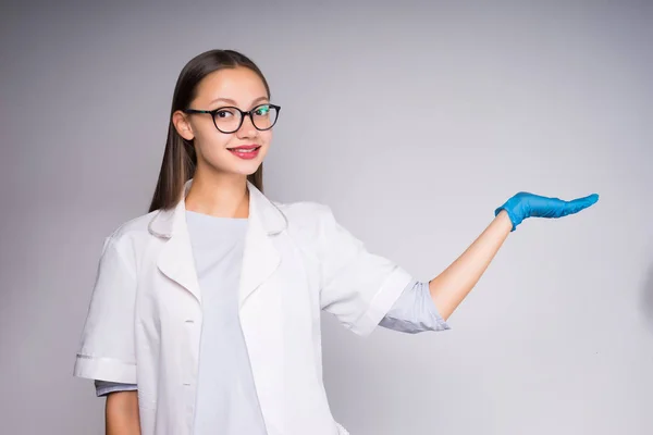 Joven enfermera en gafas muestra algo en el fondo — Foto de Stock