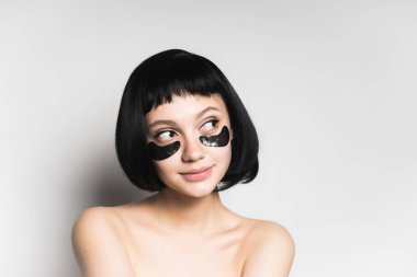 sevimli genç kız siyah saçlı gülümser, gözlerinin altında ile siyah silikon yamalar