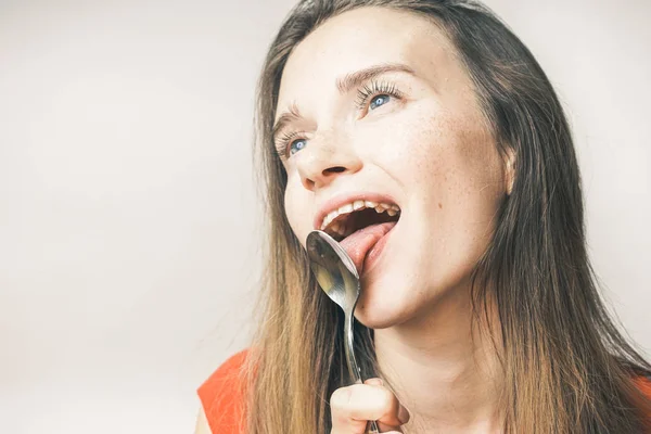 Engraçado jovem quer comer, lambe uma colher — Fotografia de Stock