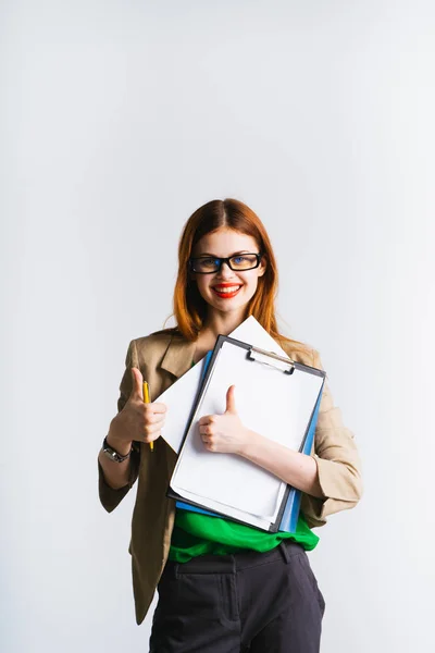 Glücklich stylisches junges Mädchen trägt eine Brille, trägt eine beige Jacke mit wichtigen Dokumenten und zeigt Daumen nach oben — Stockfoto