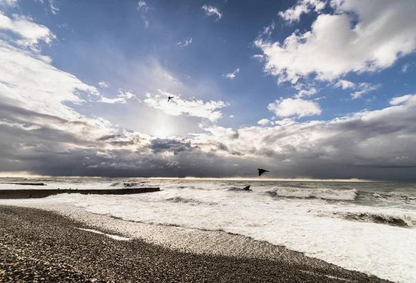 The sky is covered with gray clouds, the sea is raging at the beach of pebbles — Stock Photo, Image