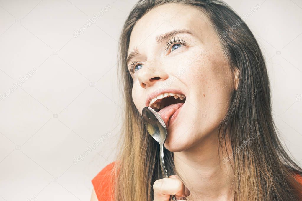 funny young girl wants to eat, licks a spoon