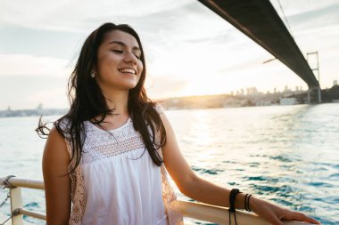 Modern bir köprü ve gülüyor, bir feribot tekne gezisi altında günbatımı yüzer adlı yatında bir güzel latin kız portresi