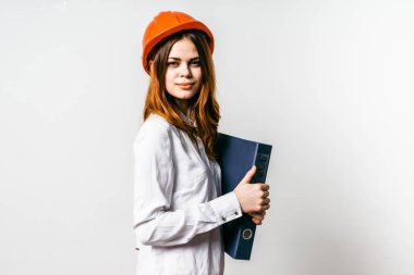 sevimli genç kız ona turuncu bir koruyucu kask başında bir Beyaz gömlekli bir klasör belgeler ile eller