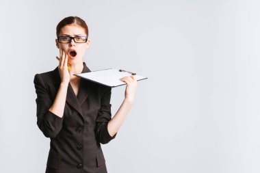 sürpriz, hayal kırıklığına uğramış genç kadın gözlük ve sıkı siyah bir takım elbise ile belgeler tutuyor