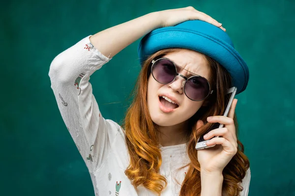 Insoddisfatto giovane ragazza dai capelli rossi in occhiali da sole e cappello parlare al telefono, urlando — Foto Stock