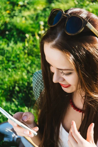 Mujer buscando algo en el móvil, mensajes de texto, adicto, se sienta en la hierba verde en el parque — Foto de Stock