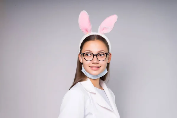 Giovane infermiera ragazza in rosa lepre orecchie su sfondo bianco — Foto Stock