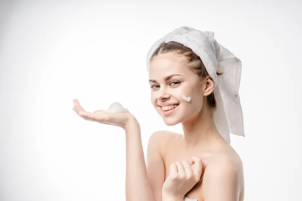 Glückliches junges Mädchen mit weißem Handtuch auf dem Kopf reinigt die Gesichtshaut mit Schaum und lächelt — Stockfoto