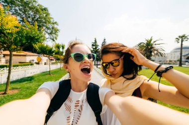 İki kız değişim öğrencileri farklı milletlerden selfie şehirde, Komik suratlar yapmak