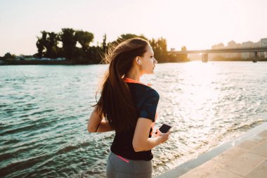 Güneş Nehri boyunca çalışan spor elbiseleri uzun saçlı genç kız