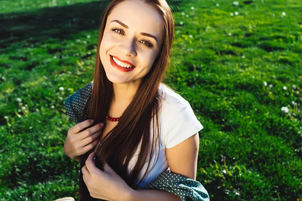 Linda mujer sonriente sentada en la hierba verde en el parque — Foto de Stock