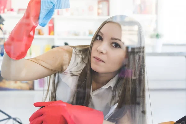 Long-haired young girl in red rubber gloves washes windows in the office — Stock Photo, Image