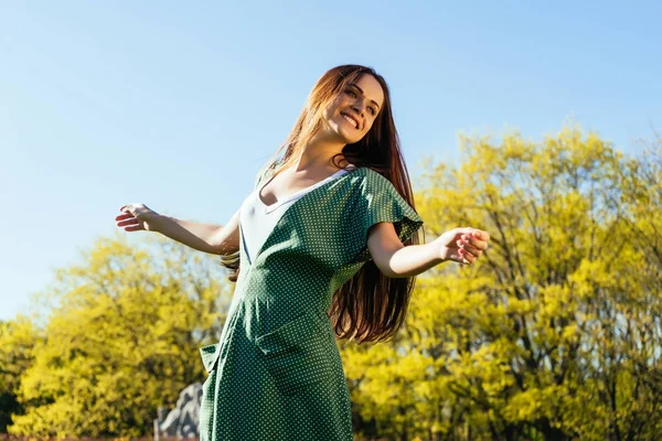 Chica feliz de pelo largo en un vestido verde largo disfruta del buen tiempo, paseos por el parque — Foto de Stock