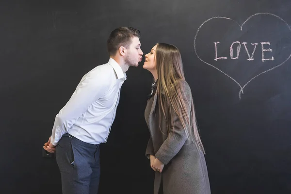 Happy young guy and girl kissing on a black background — Stock Photo, Image