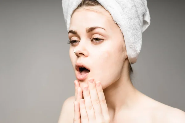 Junges Mädchen mit sauberer Haut, mit einem weißen Handtuch auf dem Kopf, das Gesicht eincremt — Stockfoto
