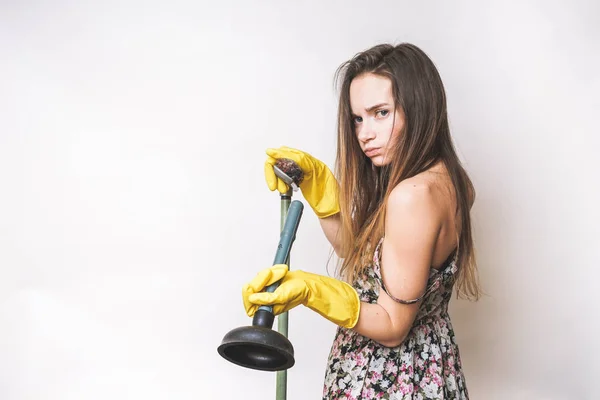 Jovem menina em luvas de borracha amarela segura um êmbolo, faz a limpeza — Fotografia de Stock