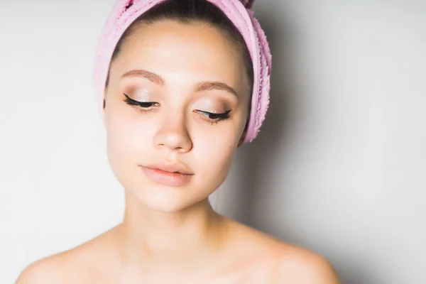 Fată frumoasă tânără cu piele curată, cu un prosop roz pe cap, se uită în jos — Fotografie, imagine de stoc