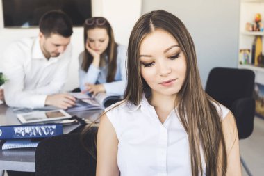 İş arkadaşları çerçevede yere bakarak bir genç şirket çalışanı
