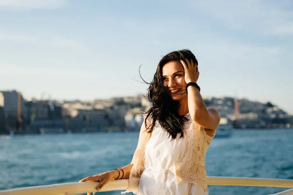 Schöne glückliche Mädchen schwimmt auf einem Boot, lächelnd auf einem Sonnenuntergang Hintergrund und eine Stadt, Istanbul — Stockfoto