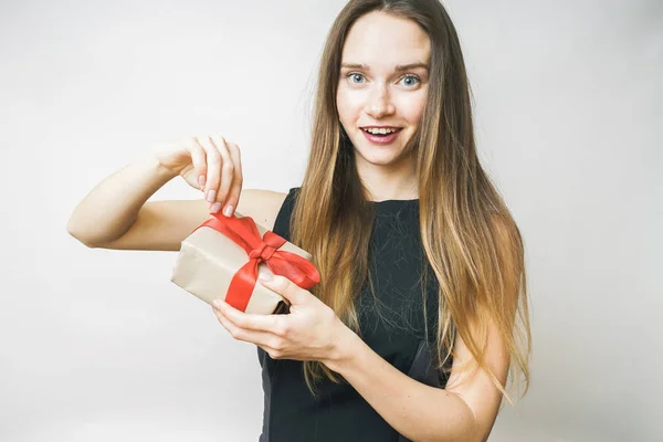 Opgewonden vrouw opening gift op een witte achtergrond — Stockfoto