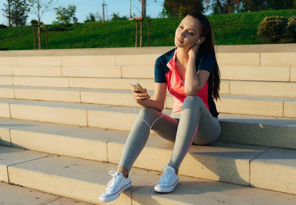 Young girl in sports uniform is resting on the steps