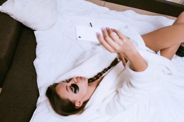 genç kız uyandım, gözleri Siyah Silikon yamalar dan çanta altında yatakta yatıyor, selfie yapar