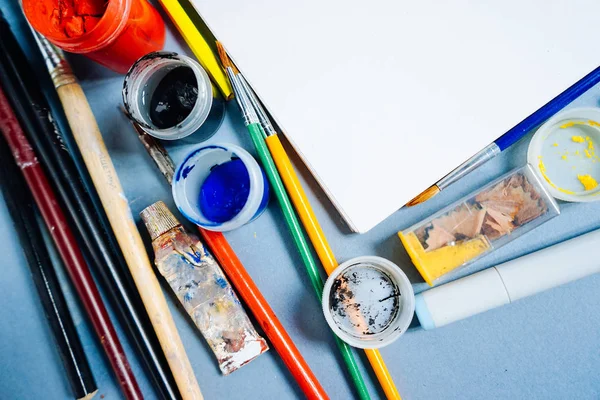 Sur la table sont les accessoires de l'artiste, couleurs colorées, papier blanc, pinceaux et crayons — Photo