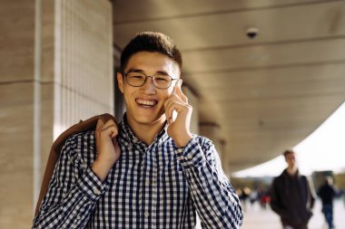 Gözlüklü başarılı genç işadamı kahkahalar, iş hakkında telefonda konuşuyor