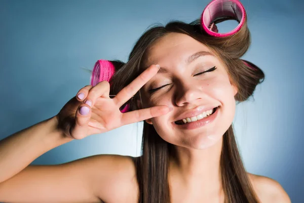 Glad ung flicka gör lockar med hjälp av stora rosa papiljotter på huvud — Stockfoto