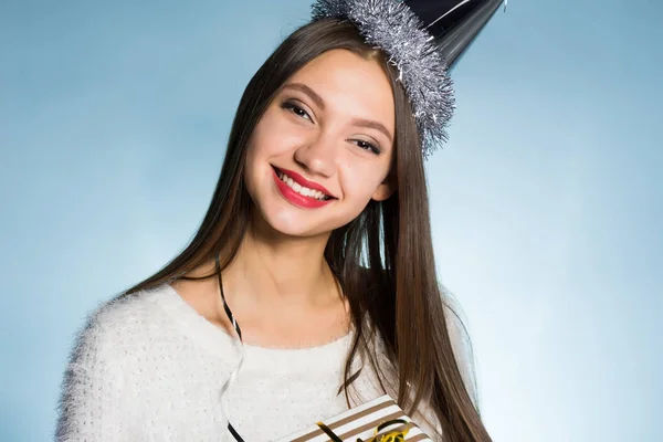 Smiling happy girl celebrating new year and christmas in a cap on her head, received a gift from friends — Stock Photo, Image