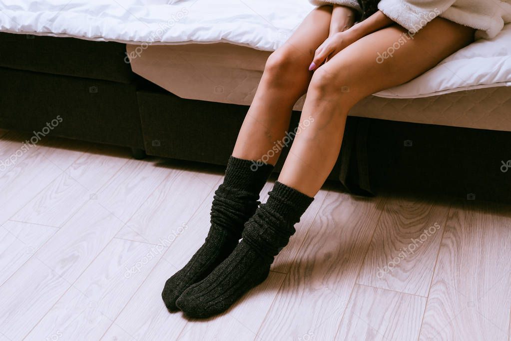 a girl with thin legs in black socks sitting on the bed, recently woke up