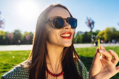 Mutlu gülümseyen komik surat kız darbe karahindiba, yaz güneş gözlüğü, günbatımı