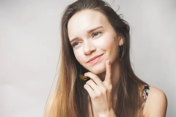 Sonhando jovem mulher com cabelo castanho em um fundo branco — Fotografia de Stock