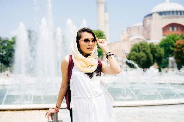 Yaz tatil günlerinde genç modern bir Müslüman kadın portresi moda gözlük elbise, uzaktan, bir caminin arka planda görünüyor. 