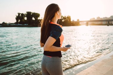 bir kız güzel spor elk içinde çalışır ve nehir kıyısında kulaklıktan müzik dinler