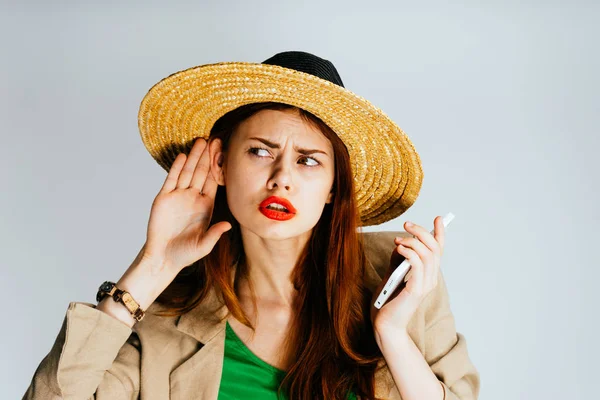 Uma menina de chapéu grande está segurando um telefone celular e ouvir sons, isolado — Fotografia de Stock