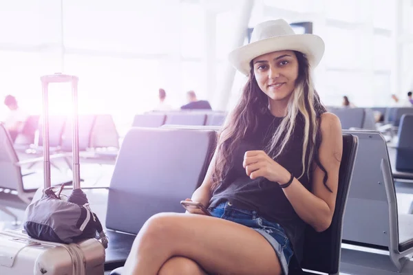 Airport woman in hat on smart phone at gate waiting in terminal. Air travel concept.Looking something in mobile,use  app — Stock Photo, Image
